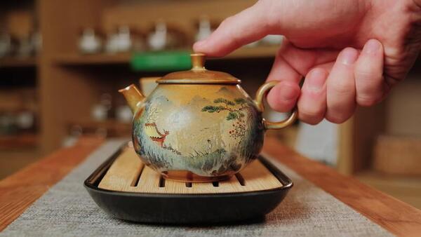Teapot pouring tea into a cup on a wooden tray
